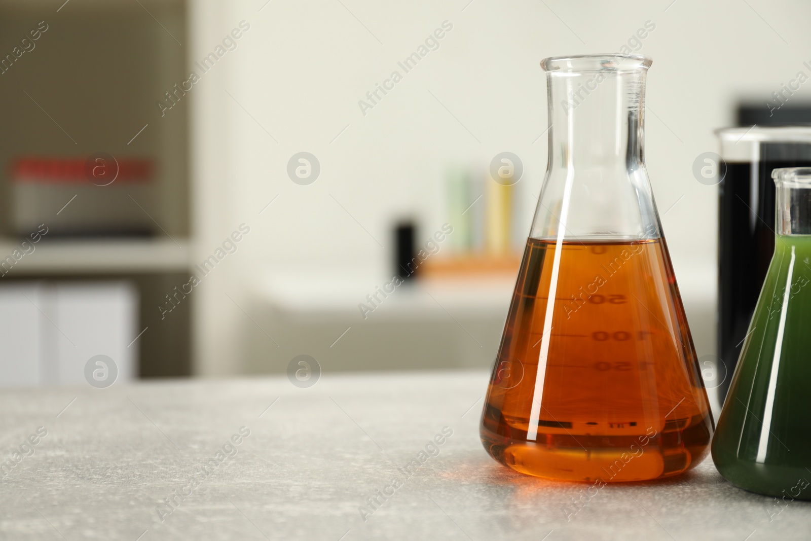 Photo of Flasks and beaker with different types of crude oil on light grey table, space for text