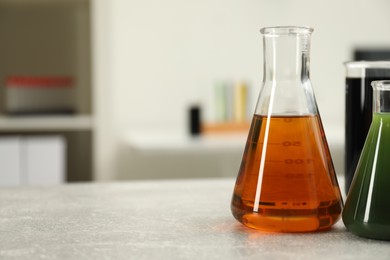 Photo of Flasks and beaker with different types of crude oil on light grey table, space for text