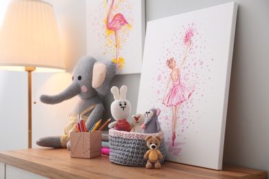 Pictures and stationery with toys on wooden table in children's room. Interior design