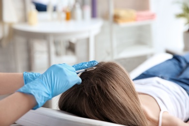 Photo of Young woman with hair loss problem receiving injection in clinic