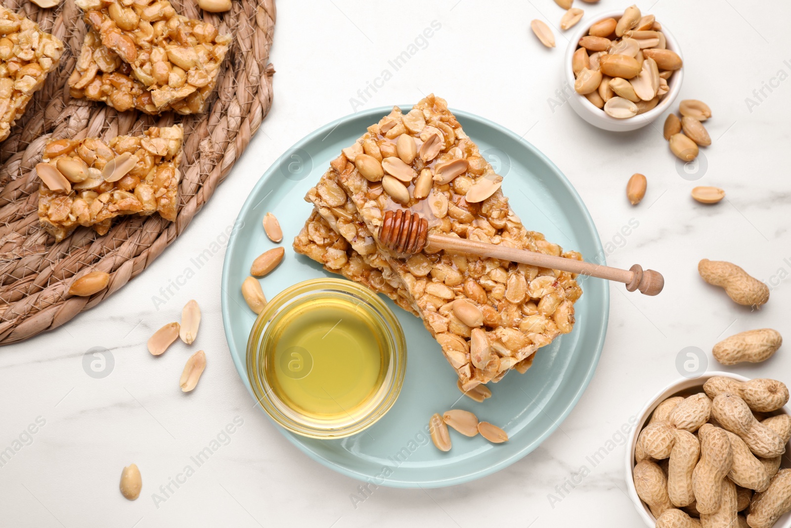Photo of Delicious peanut bars (kozinaki) and ingredients on white marble table, flat lay