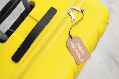 Yellow suitcase with TRAVEL INSURANCE label on floor, top view