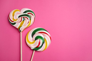 Photo of Sticks with different colorful lollipops on pink background, flat lay. Space for text