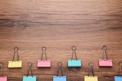 Photo of Binder clips on wooden background, flat lay. Space for text