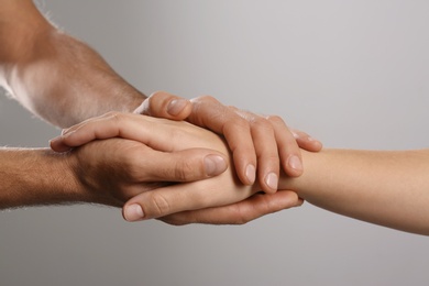 Man comforting woman on grey background, closeup of hands. Help and support concept