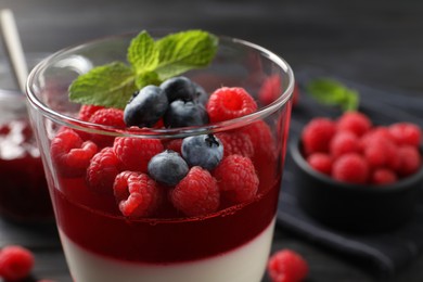 Photo of Delicious panna cotta with berries in glass dish, closeup