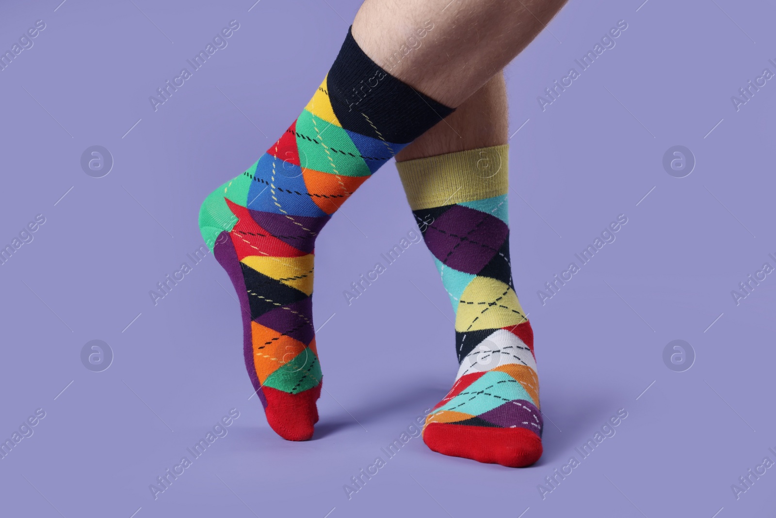 Photo of Man in different colorful socks on violet background, closeup