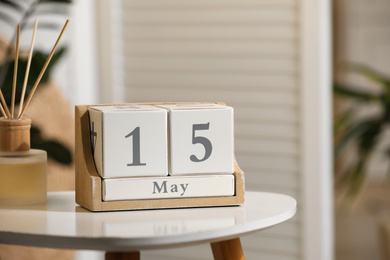 Wooden block calendar and aromatic reed air freshener on white table indoors