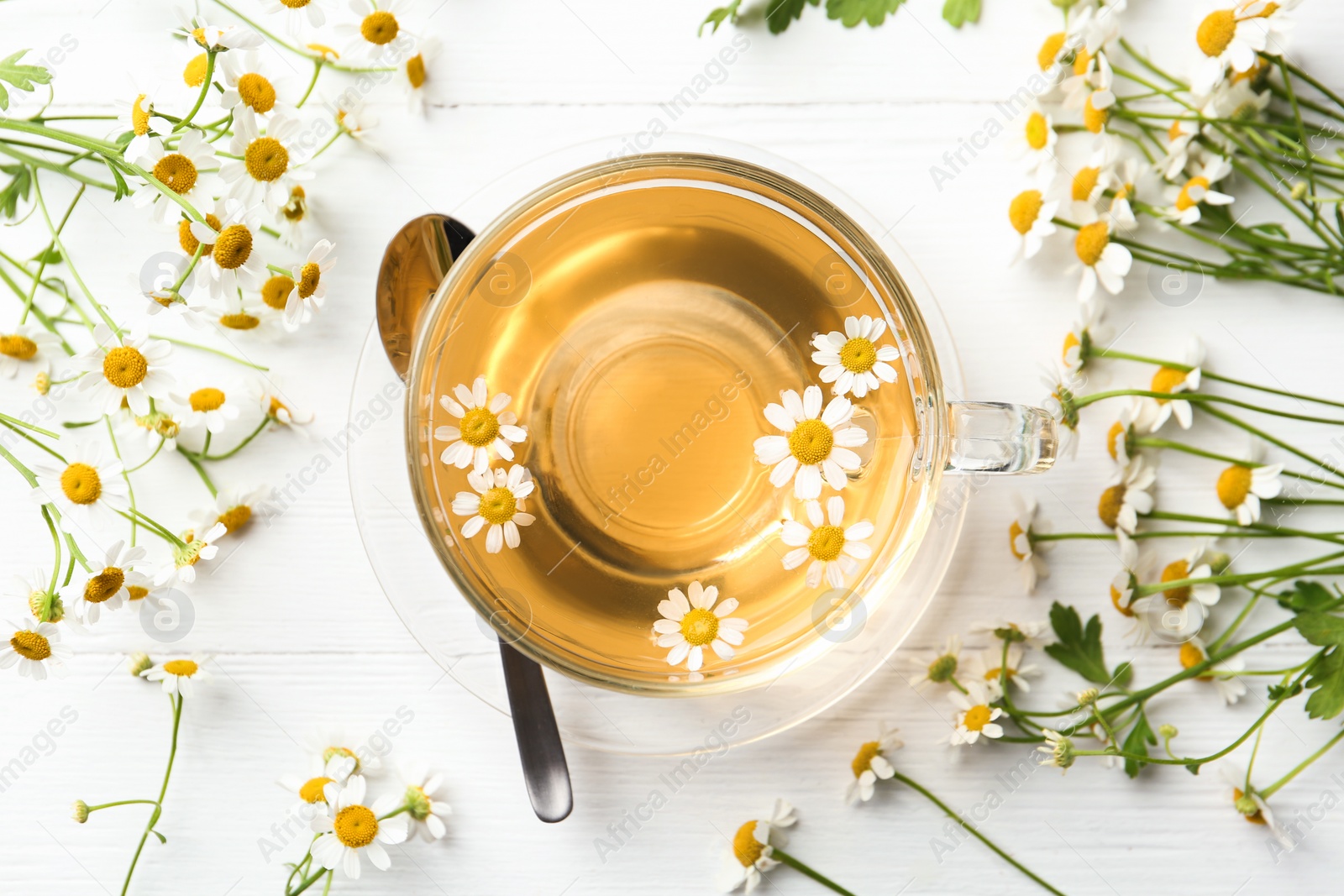 Photo of Flat lay composition with cup of tea and chamomile flowers on white wooden table