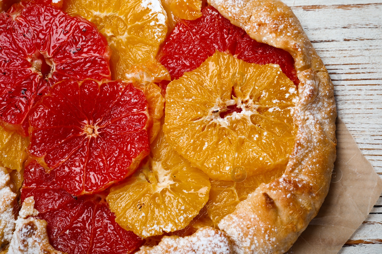 Photo of Delicious galette with citrus fruits on white wooden table, top view