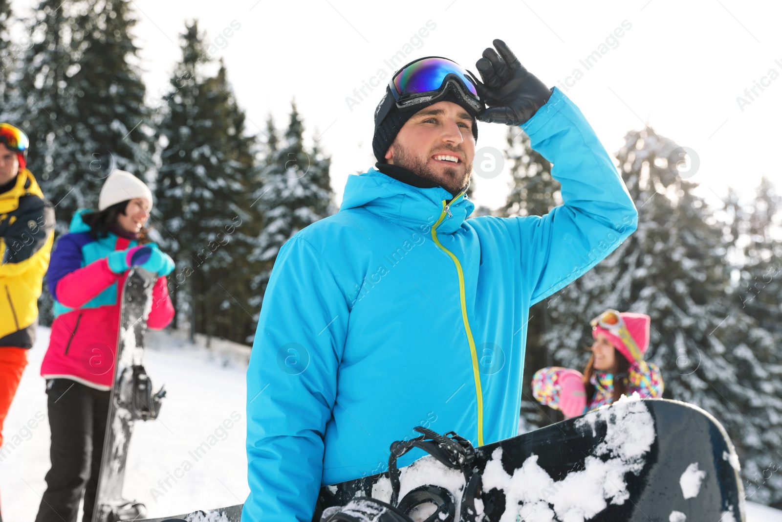 Photo of Young snowboarder with friends in snowy mountains. Winter vacation