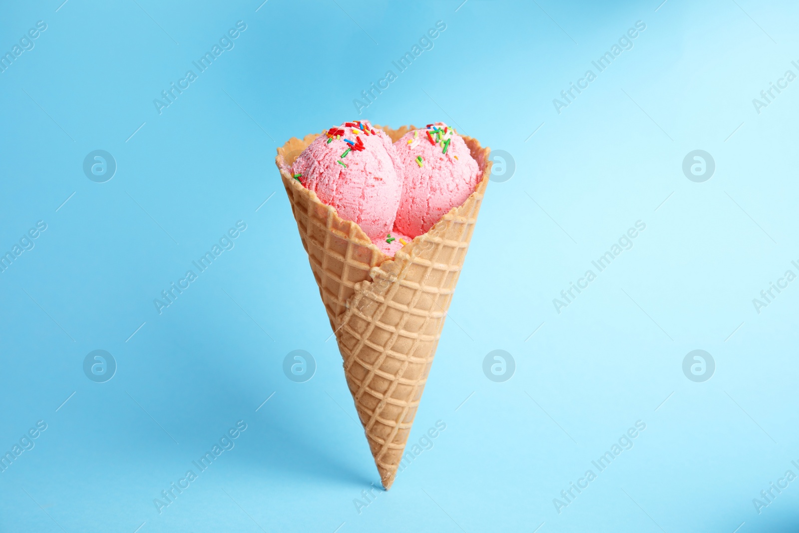 Photo of Delicious ice cream in wafer cone on blue background