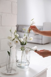 Woman taking beautiful flowers from vase indoors, closeup