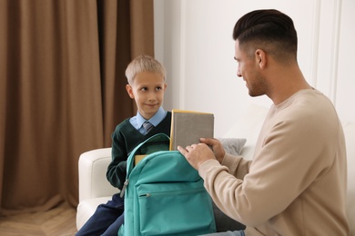 Photo of Father helping his little child get ready for school at home