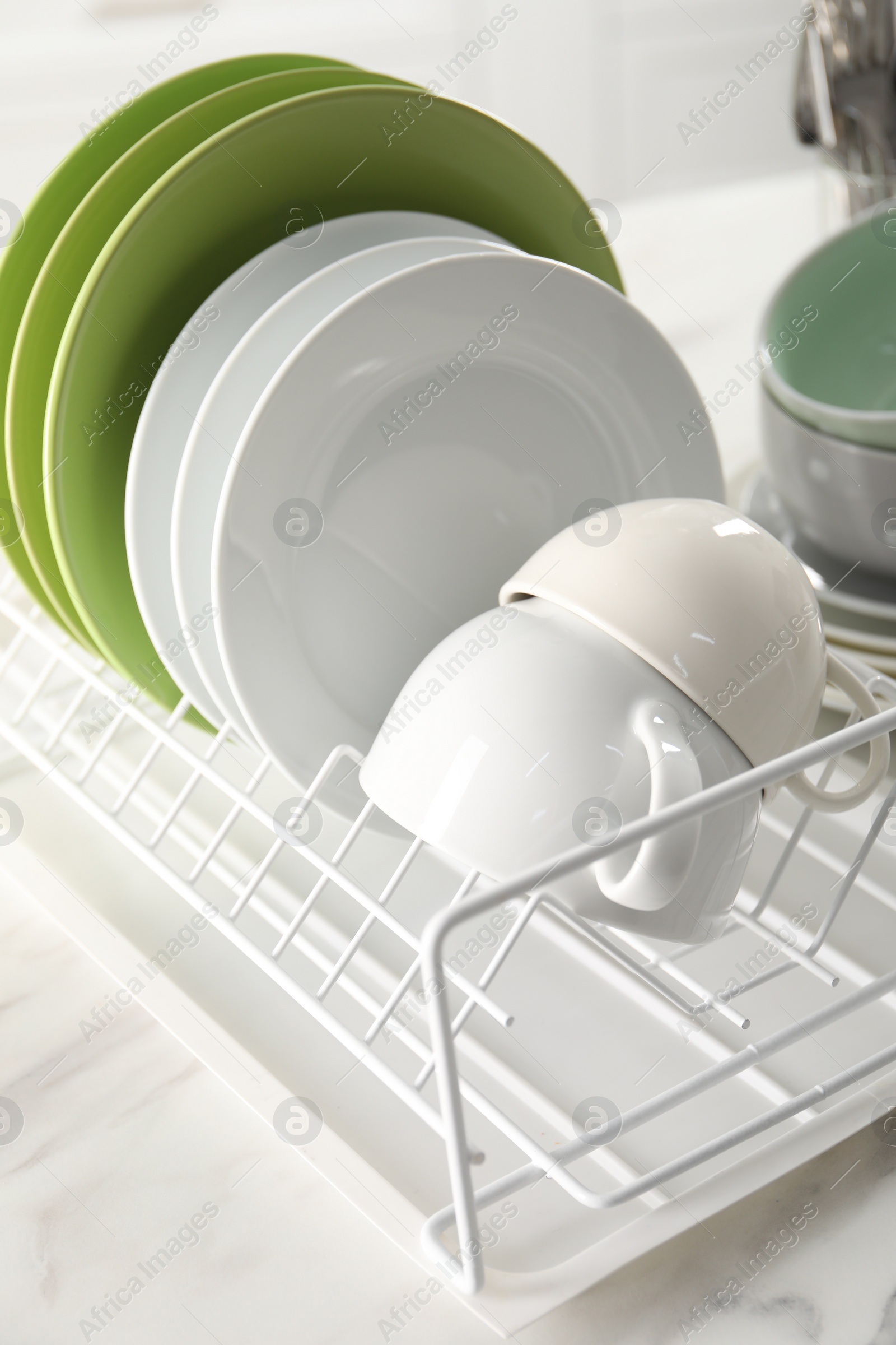 Photo of Drainer with cups and plates on white table, closeup