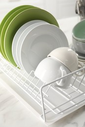 Photo of Drainer with cups and plates on white table, closeup