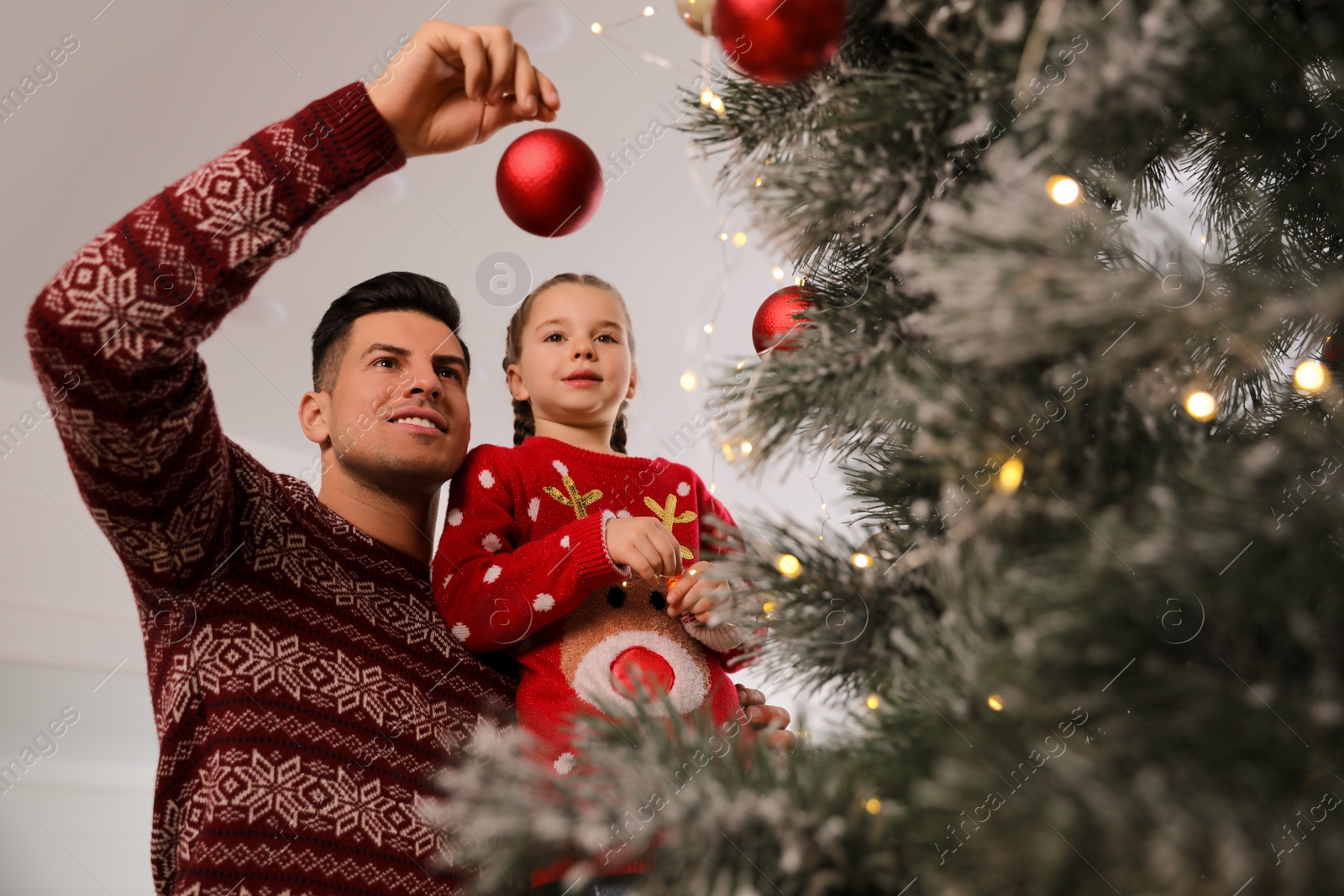 Photo of Happy father with his cute daughter decorating Christmas tree together indoors