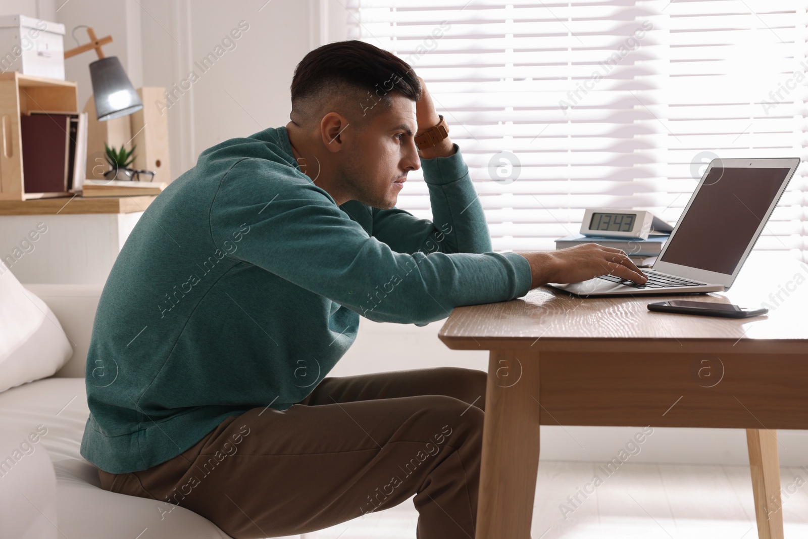 Photo of Man with poor posture using laptop at table indoors