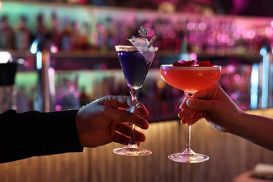 Photo of Man and woman holding glasses with fresh alcoholic cocktails in bar, closeup