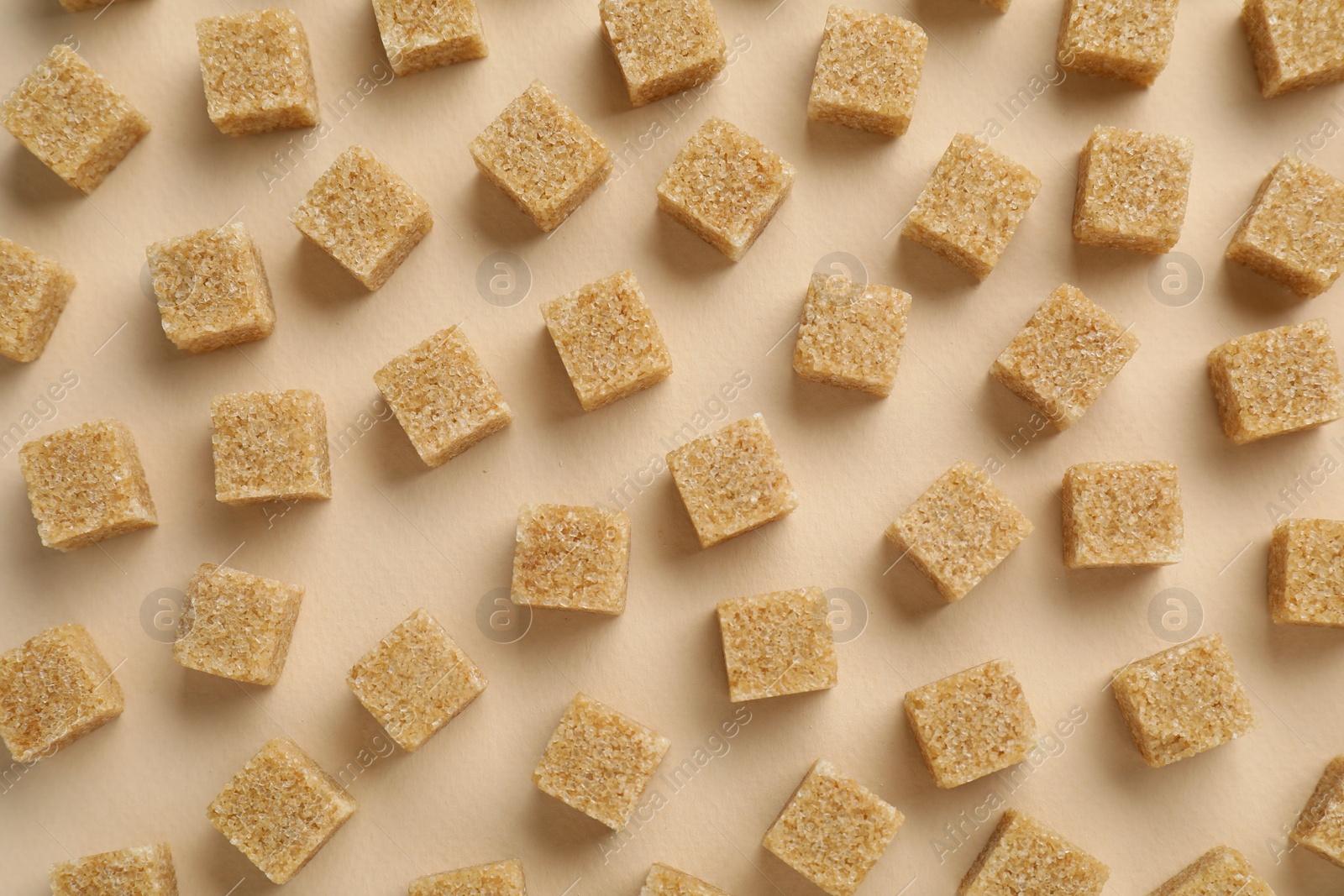 Photo of Brown sugar cubes on beige background, top view