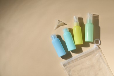 Photo of Cosmetic travel kit and plastic bag on beige background, flat lay with space for text. Bath accessories