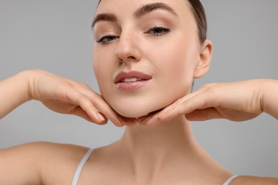 Photo of Beautiful woman touching her chin on grey background