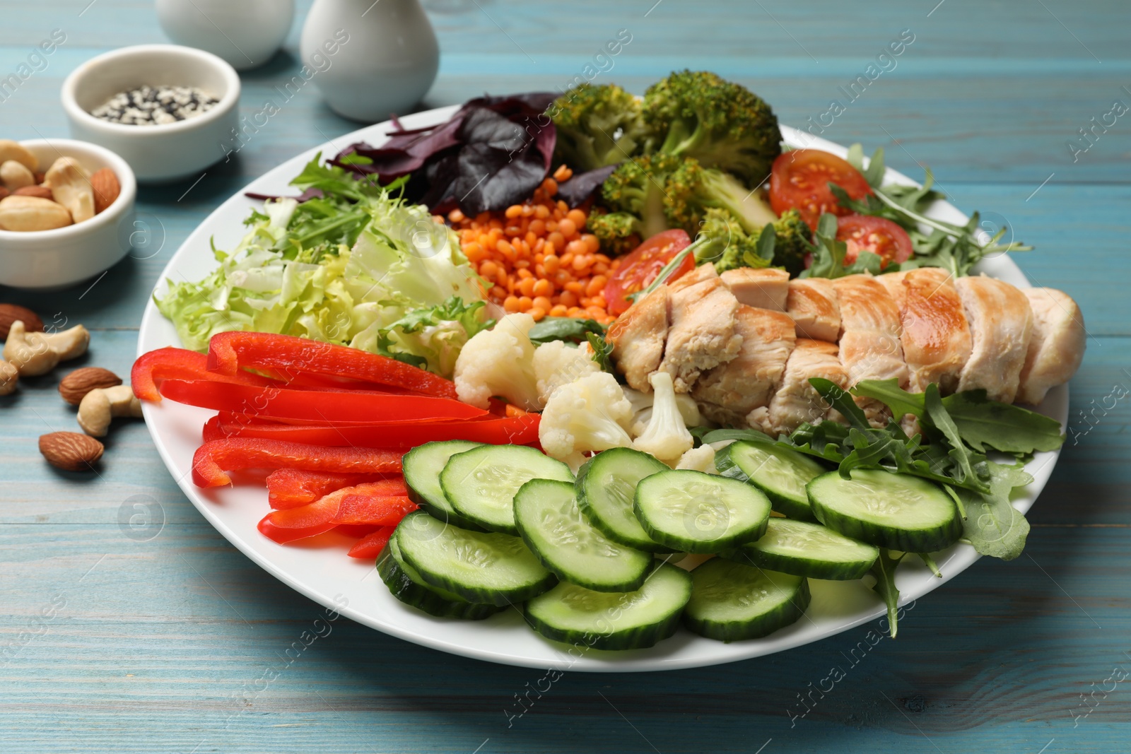 Photo of Balanced diet and healthy foods. Plate with different delicious products on light blue wooden table