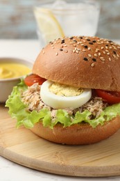 Photo of Delicious sandwich with tuna, boiled egg and vegetables on wooden board, closeup