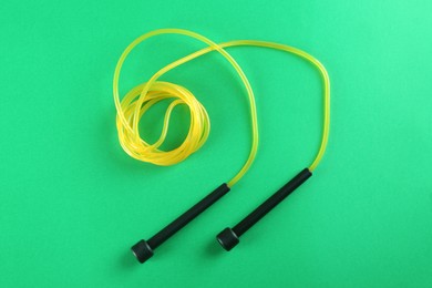 Photo of Skipping rope on green background, top view. Sports equipment