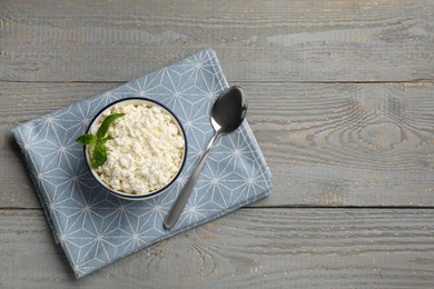 Delicious fresh cottage cheese with basil on grey wooden table, flat lay. Space for text