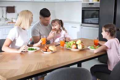 Photo of Happy family having breakfast together at table in modern kitchen