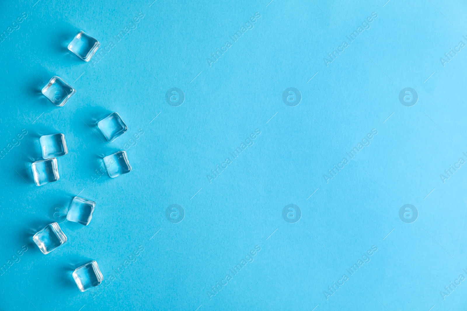 Photo of Crystal clear ice cubes on blue background, flat lay. Space for text