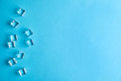 Photo of Crystal clear ice cubes on blue background, flat lay. Space for text