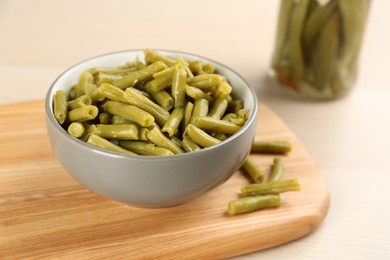 Photo of Canned green beans in bowl on wooden board