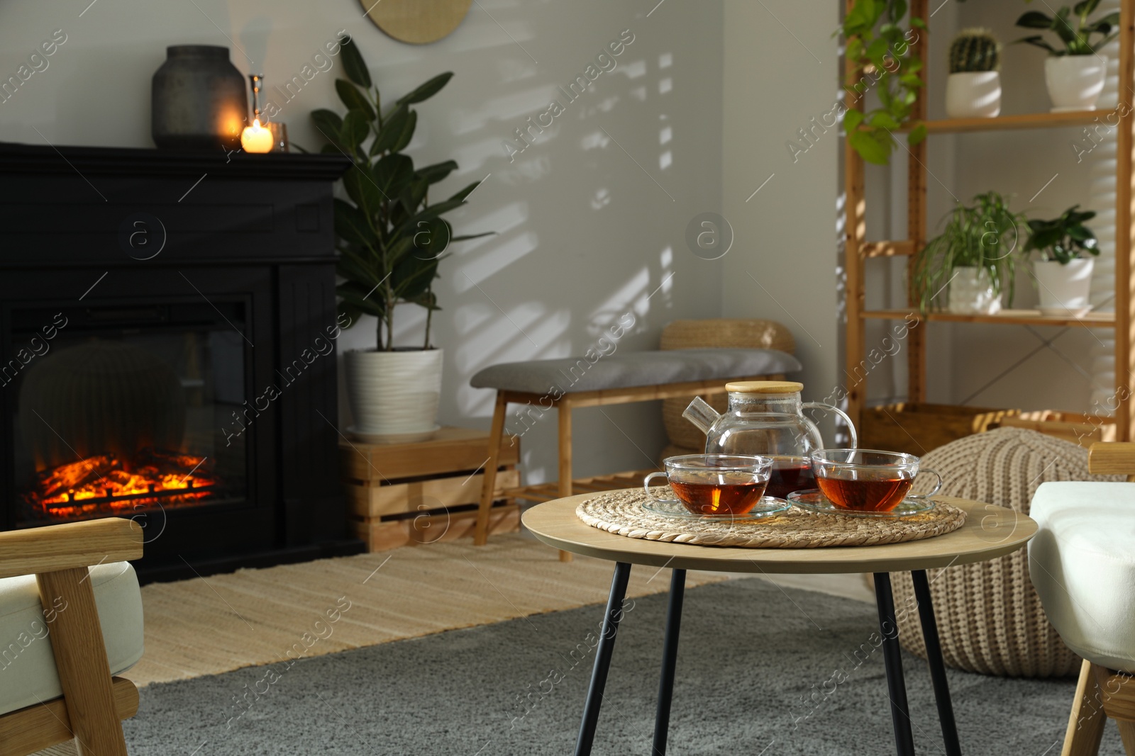 Photo of Stylish fireplace near coffee table with tea in cosy living room. Interior design