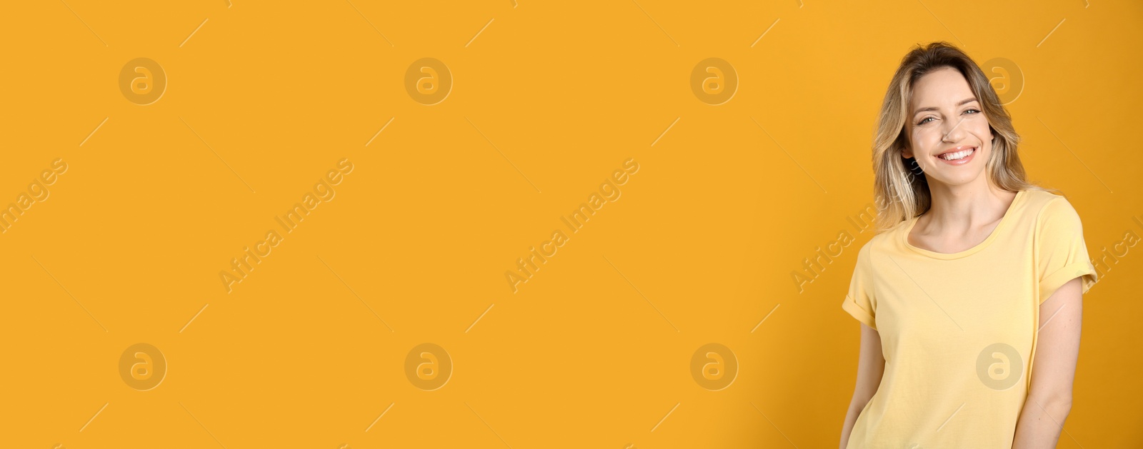 Photo of Portrait of happy young woman with beautiful blonde hair and charming smile on yellow background. Space for text