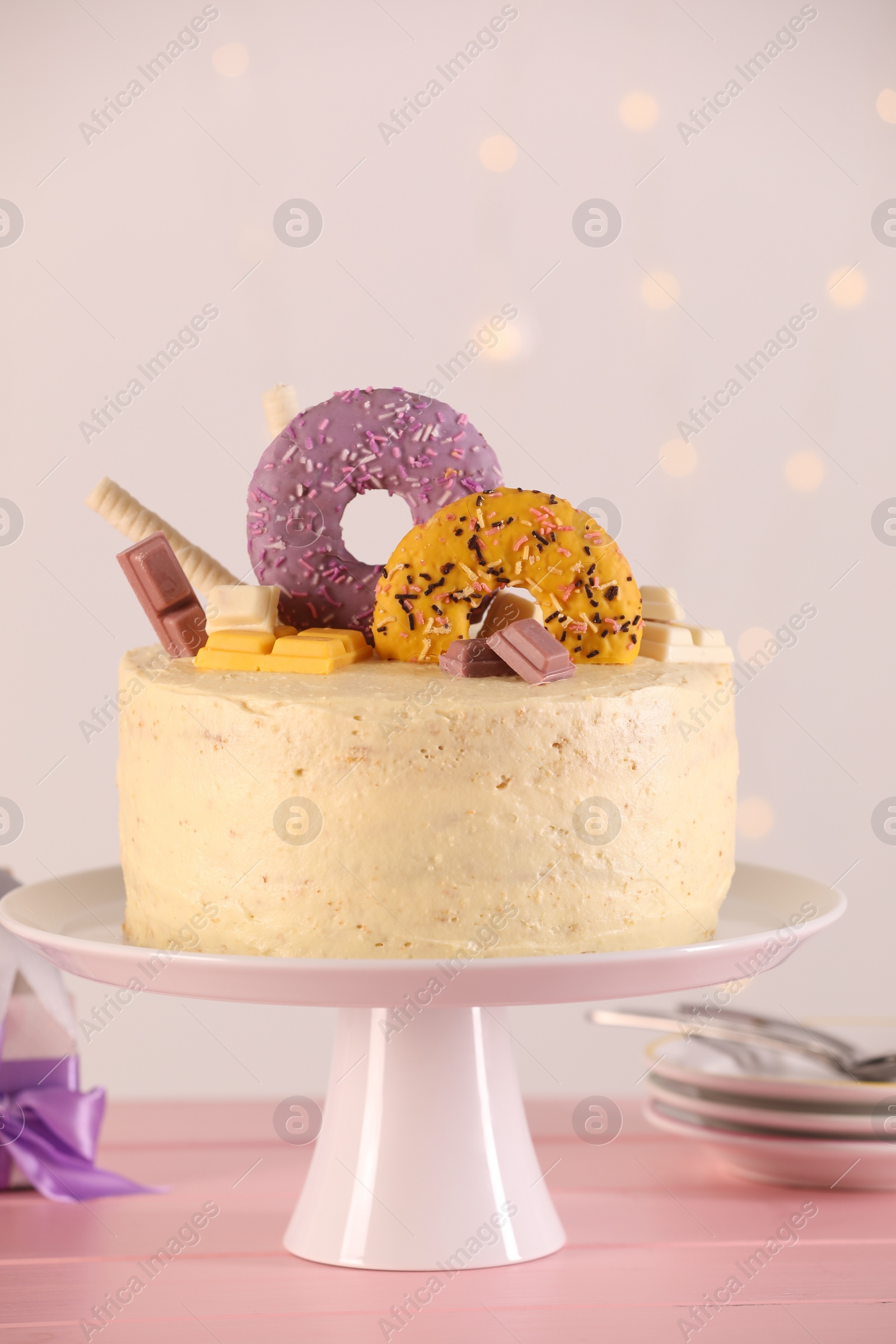 Photo of Delicious cake decorated with sweets on pink wooden table