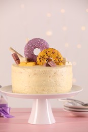 Delicious cake decorated with sweets on pink wooden table