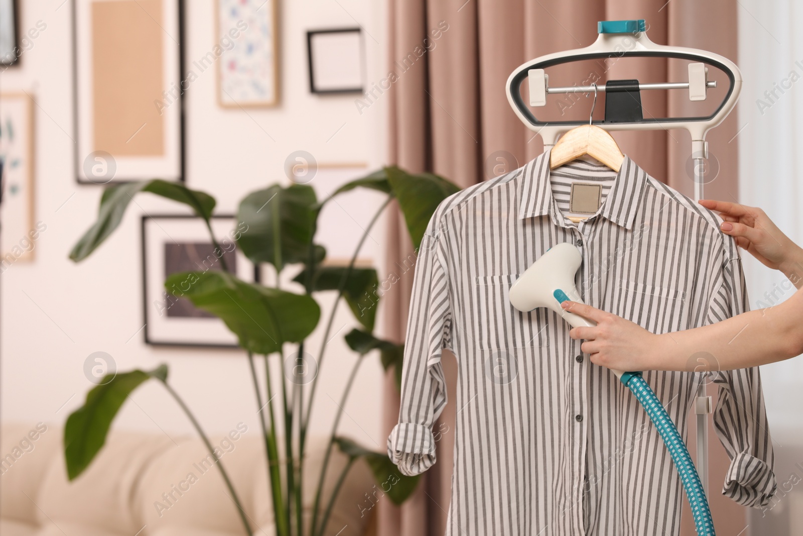 Photo of Woman steaming shirt on hanger at home, closeup. Space for text