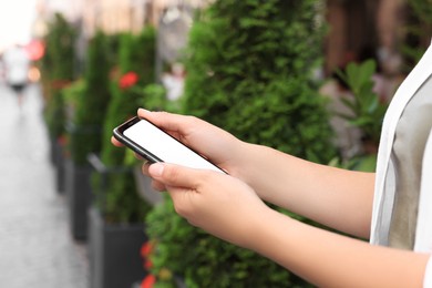 Young woman using smartphone outdoors, closeup view