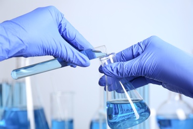 Doctor pouring blue liquid into flask, closeup. Laboratory analysis