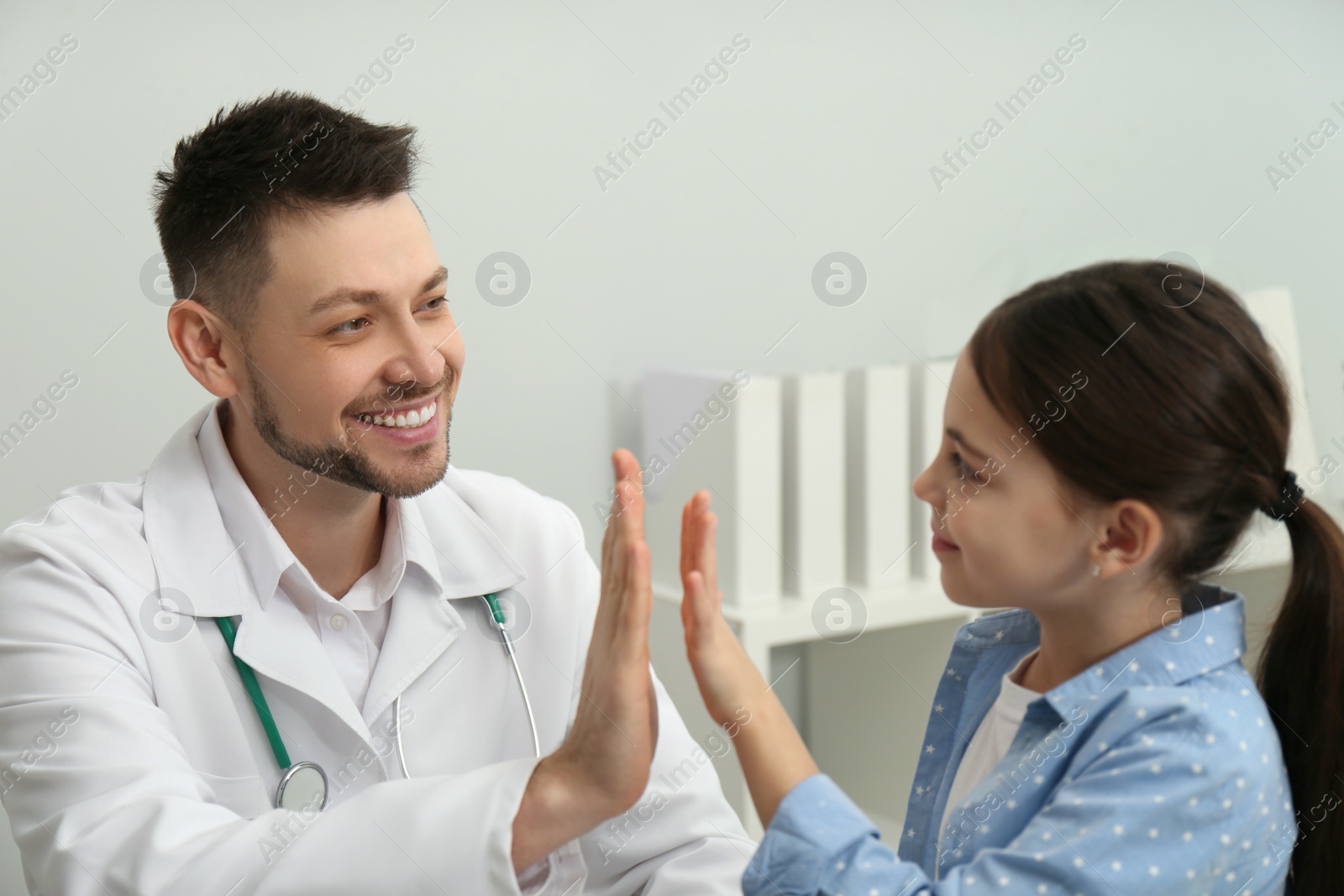 Photo of Pediatrician giving high five to little girl in hospital