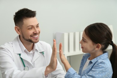 Photo of Pediatrician giving high five to little girl in hospital