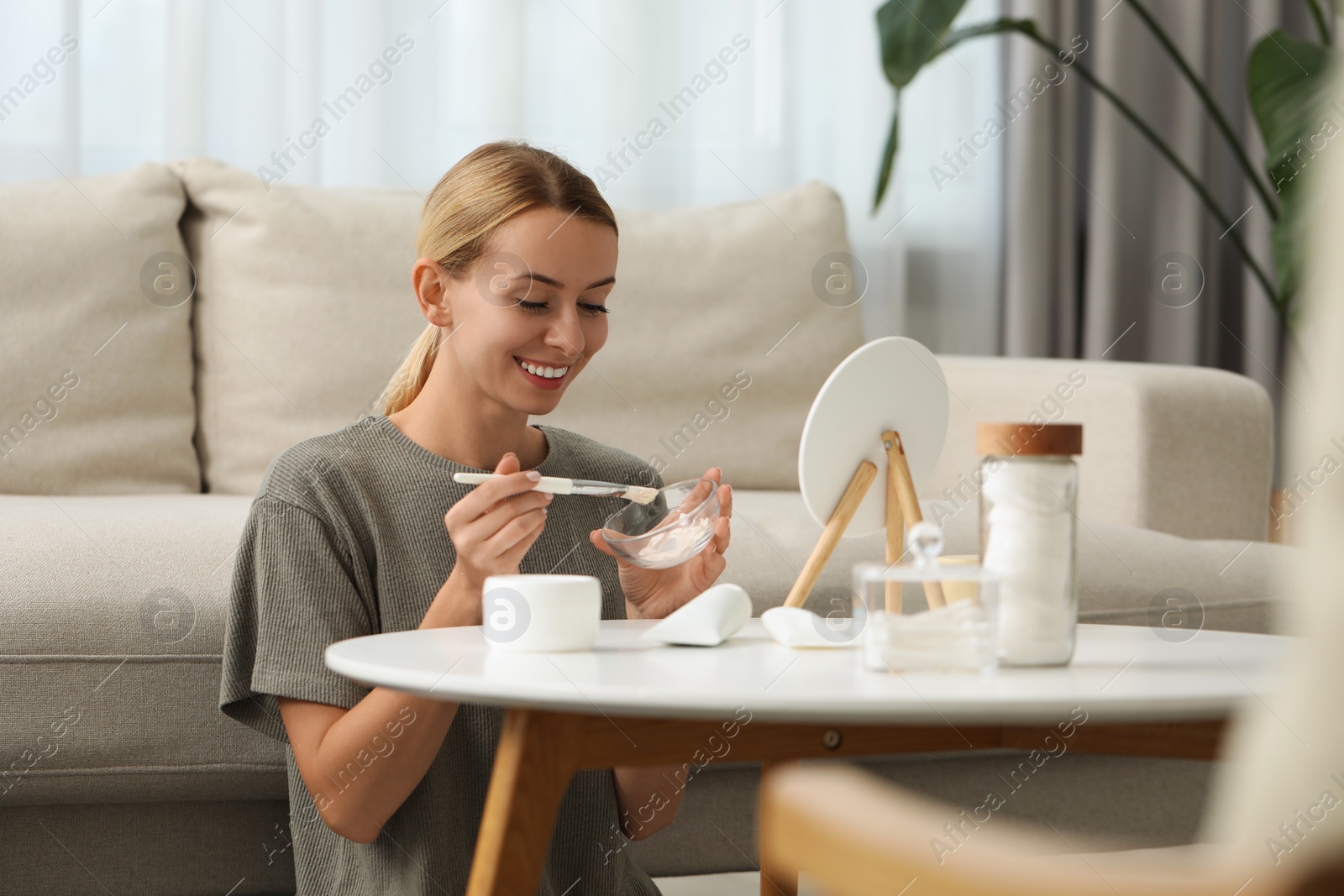 Photo of Young woman preparing face mask in front of mirror at home. Spa treatments