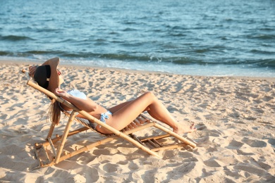 Photo of Young woman relaxing in deck chair on beach