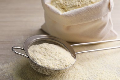 Photo of Sieve with quinoa flour on wooden table, closeup