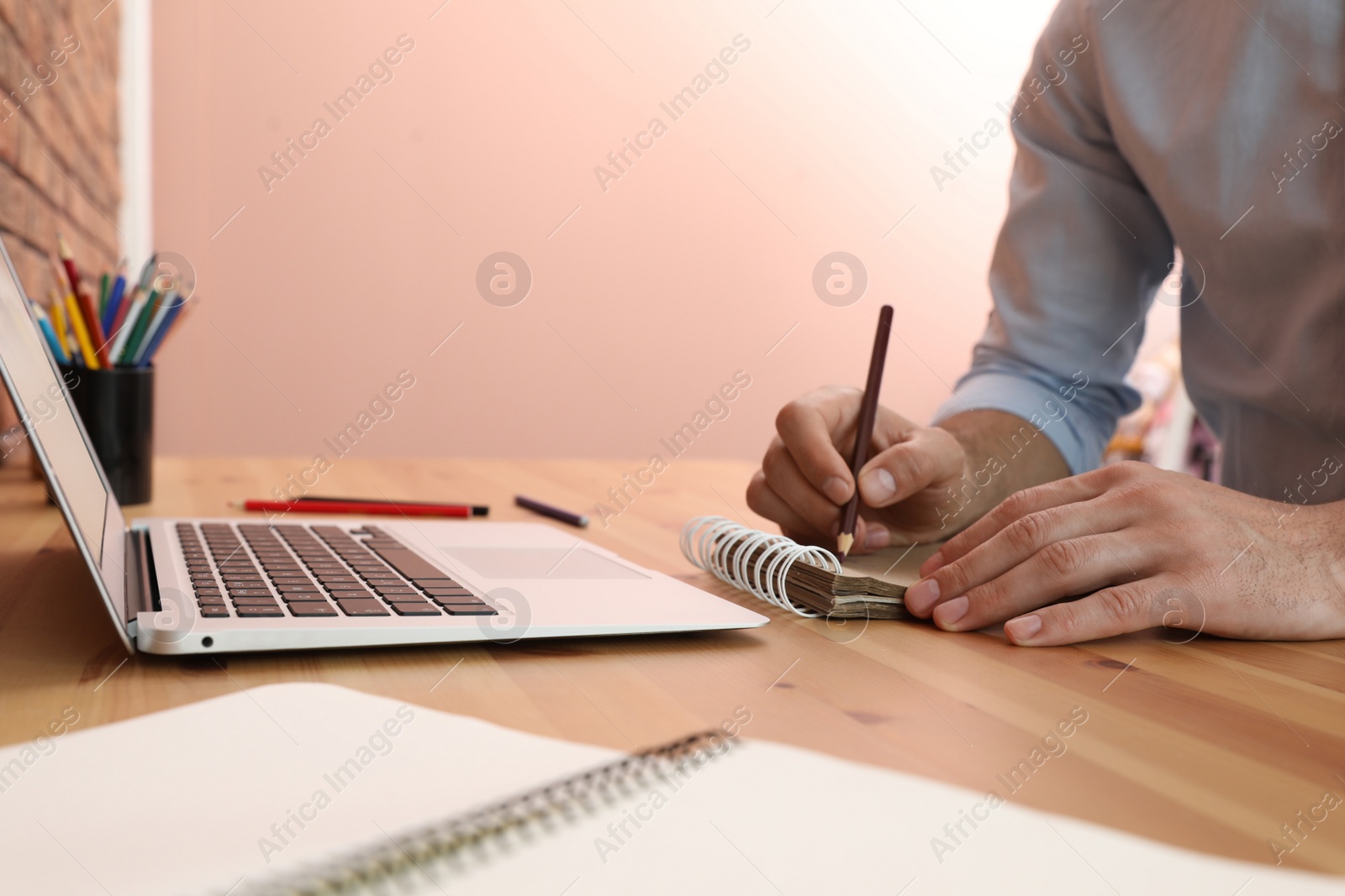 Photo of Man drawing in notebook at online lesson indoors, closeup. Distance learning