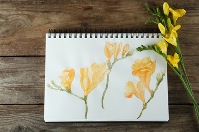 Photo of Beautiful drawing of freesia and flowers on wooden table, flat lay