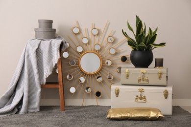 Stylish room interior with storage trunks, wooden stool and mirror