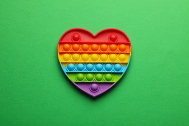 Photo of Heart shaped rainbow pop it fidget toy on green background, top view